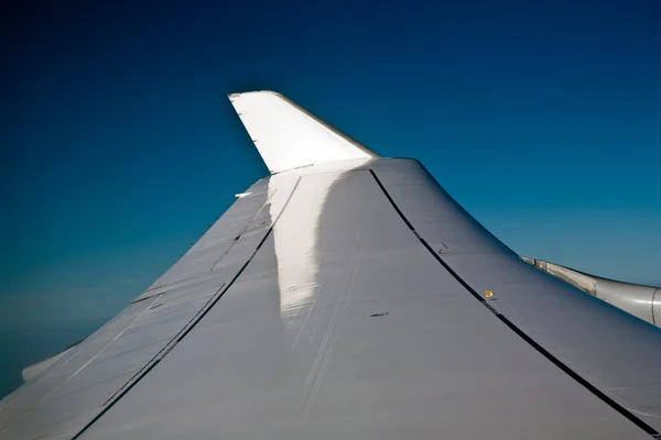 Vleugels van een vliegtuig in de blauwe heldere lucht — Stockfoto