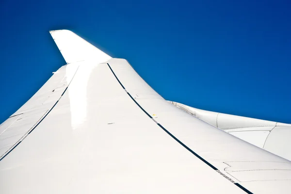 Skrzydła samolotu na błękitnym bezchmurnym niebie — Zdjęcie stockowe