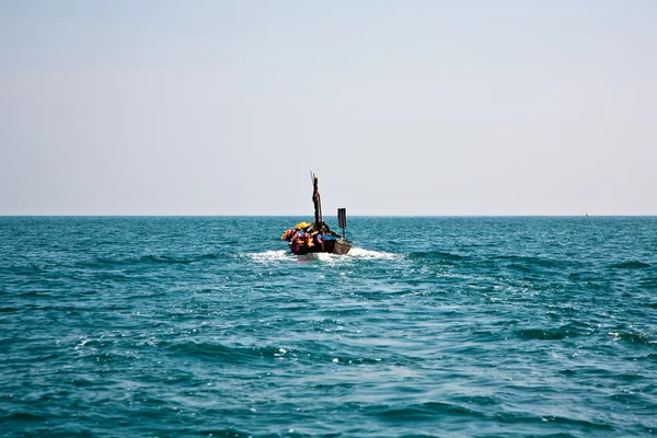 Рыбак направляет свою маленькую деревянную лодку в открытое море, чтобы пойти — стоковое фото