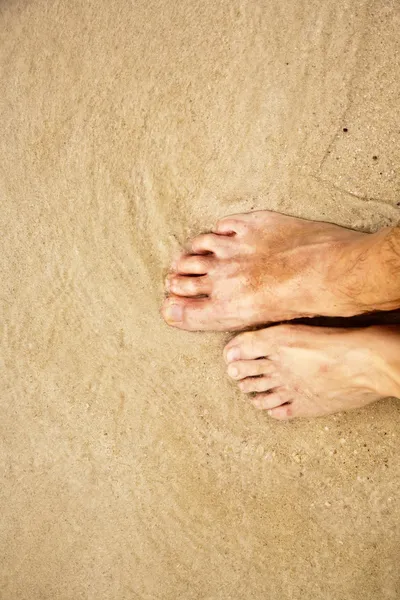 Pies de un hombre en la arena fina rodeado de agua salada — Foto de Stock