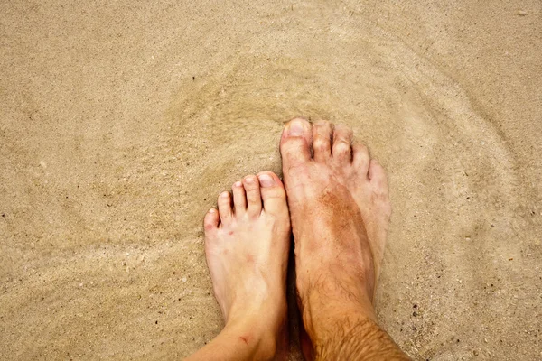 Ноги чоловіка в дрібному піску в оточенні солоної води — стокове фото