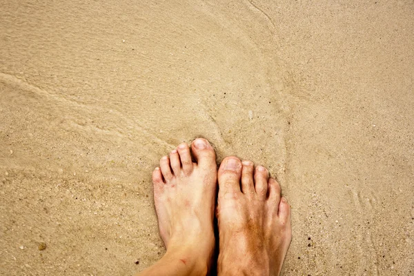Ноги человека в мелком песке в окружении соленой воды — стоковое фото