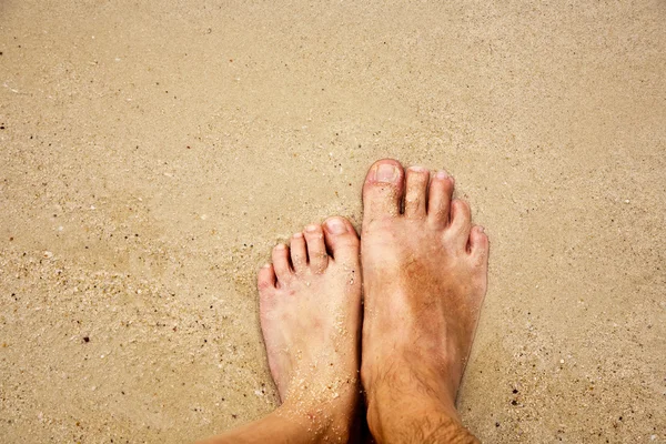 Pés de um homem na areia fina cercada por água salgada — Fotografia de Stock