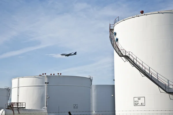 Serbatoi bianchi in tank farm con cielo blu e aerei in avvicinamento — Foto Stock