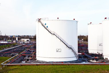 Tank çiftliğinde benzin ve petrol için mavi gökyüzü olan beyaz tanklar