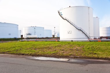 Tank çiftliğinde benzin ve petrol için mavi gökyüzü olan beyaz tanklar