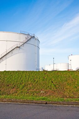 Tank çiftliğinde benzin ve petrol için mavi gökyüzü olan beyaz tanklar