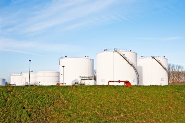 Tank çiftliğinde benzin ve petrol için mavi gökyüzü olan beyaz tanklar