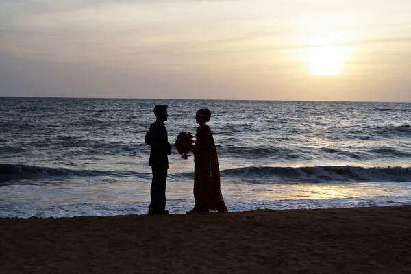 Одружена пара стоїть щасливою на пляжі під час заходу сонця — стокове фото