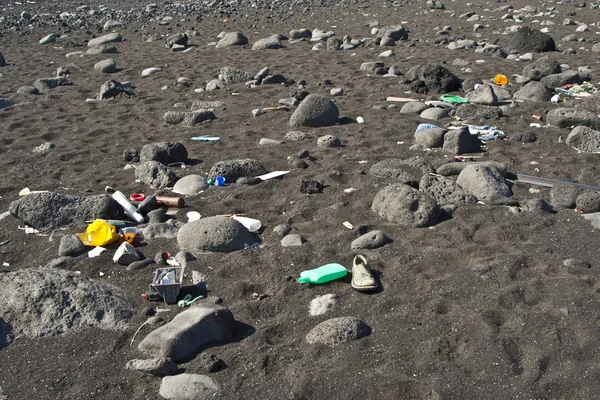 Black vulcanic beach is littered by garbage of campers and touri — Stock Photo, Image