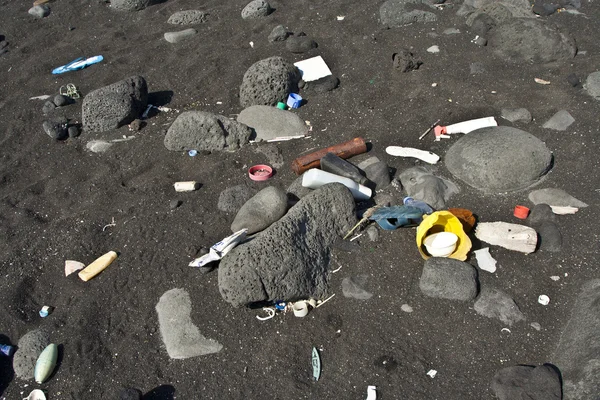 Praia vulcânica preta é repleta de lixo de campistas e touri — Fotografia de Stock