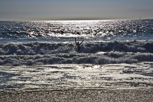 Fare il bagno al tramonto tra le onde sulla spiaggia — Foto Stock