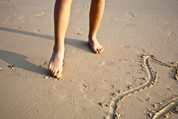 Füße eines Jungen malt Figuren in den feinen Sand der Schönheit — Stockfoto