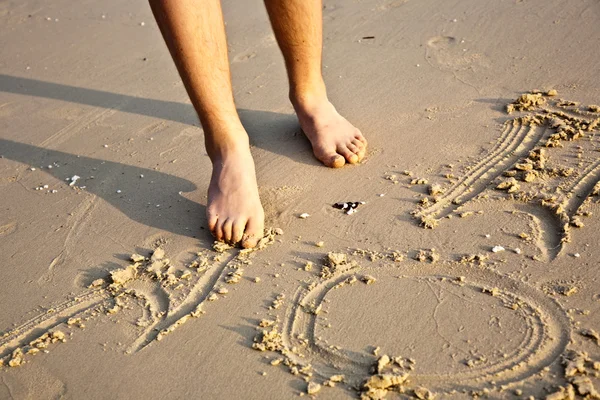 Los pies de un niño está pintando figuras en la arena fina de la beauti — Foto de Stock