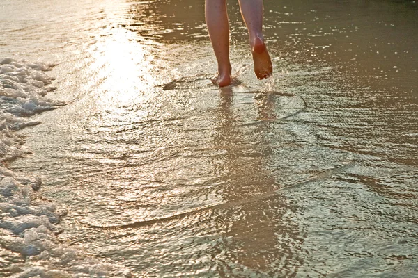 Alimentazione di camminare l'uomo in acqua in spiaggia in controluce — Foto Stock