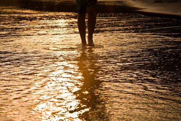 Kanál chůze člověka na vodu na pláži v podsvícení — Stock fotografie