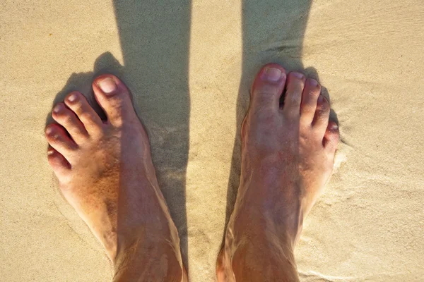 Pieds d'un homme dans le sable fin — Photo