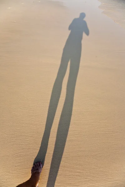 Long corps ombre d'un homme dans le sable fin de la plage, pieds est — Photo