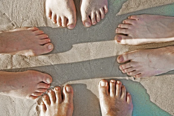 Fötter av en familj i fin sand av den ilandflutna, grupperade i en c — Stockfoto