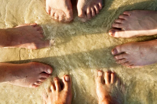 Voeten van een gezin in het fijne zand van het gestrande, gegroepeerd in een c — Stockfoto