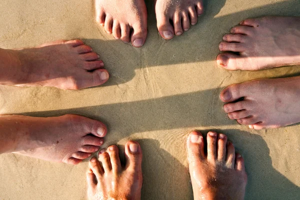 Nohy rodiny v jemném písku břeh, seskupené v c — Stock fotografie