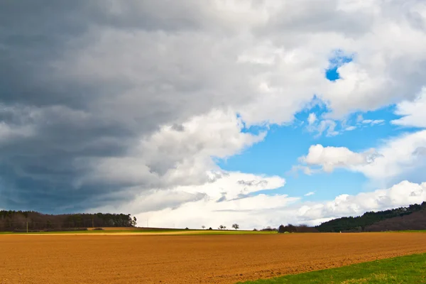 Dunkle Wolken und blauer Himmel über Feldern — Stockfoto