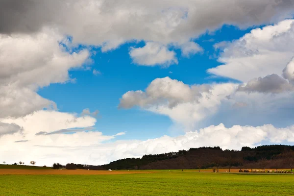 Dunkle Wolken über Feldern im Frühling — Stockfoto