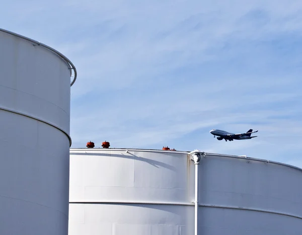 Tank sahası ile mavi gökyüzü ve uçak yaklaşırken beyaz tankları — Stok fotoğraf