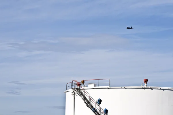 Белые танки на танковой ферме с голубым небом и приближающимся самолетом — стоковое фото