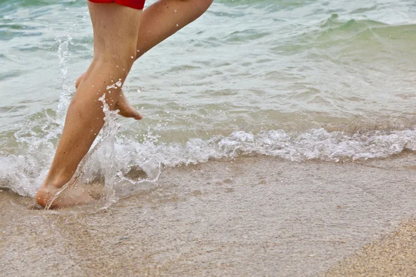 ビーチ沿いを走っている少年の足 — ストック写真