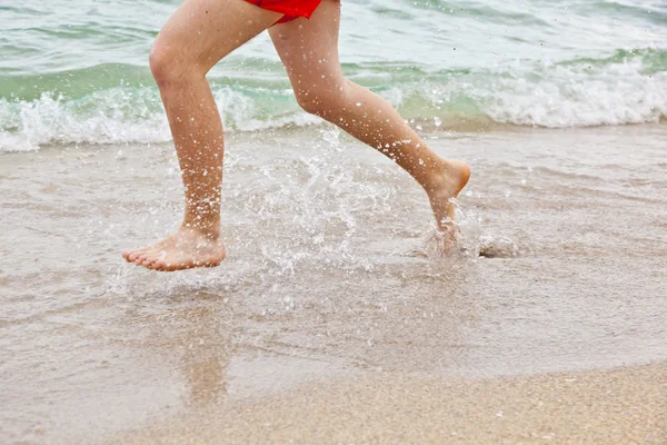 Stóp chłopiec biegną wzdłuż plaży — Zdjęcie stockowe