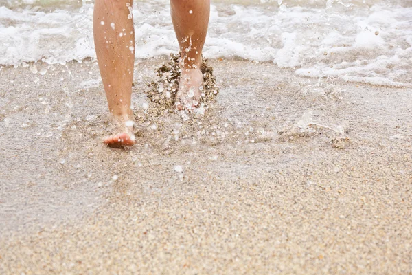 Fötter av pojke promenader längs stranden — Stockfoto