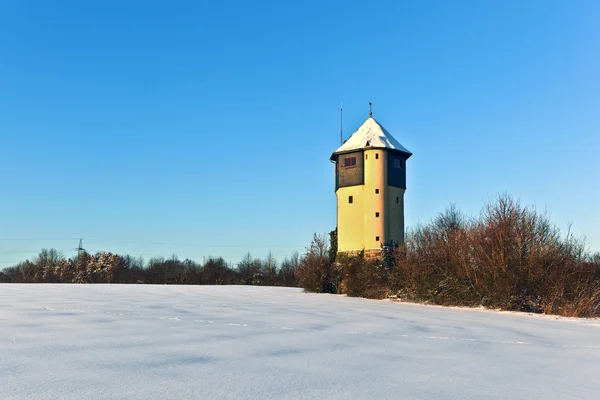 Водонапорная башня в заснеженных полях — стоковое фото
