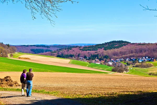 Paisagem com campos e uma aldeia com colinas no horizonte — Fotografia de Stock