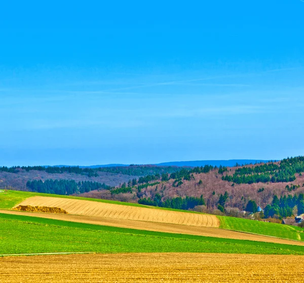 Krajobraz z pola i wioski ze wzgórza na horyzoncie — Zdjęcie stockowe