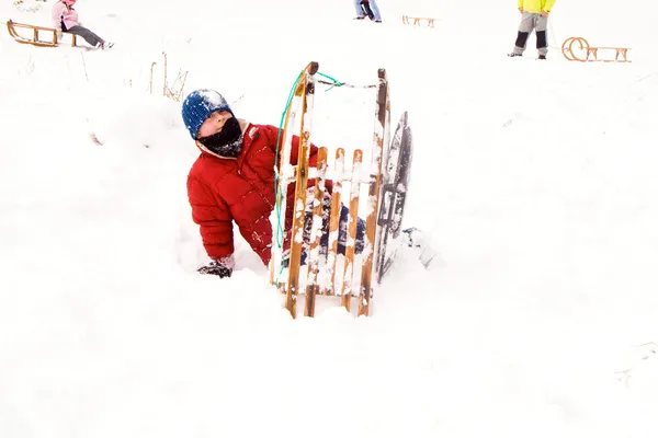 Niño bajando en trineo por la colina en nieve, invierno blanco — Foto de Stock
