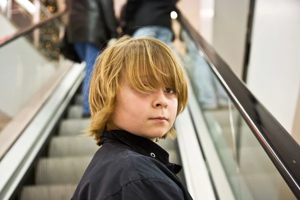 Criança está sorrindo confiante em uma escada em um shopping — Fotografia de Stock