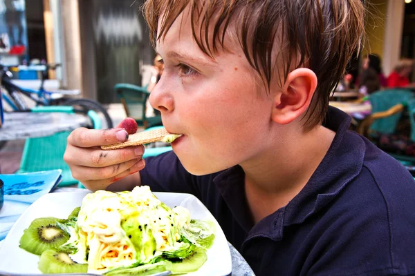 Criança está comendo gelado em uma mesa ao ar livre — Fotografia de Stock
