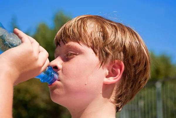 Young boy drinks water out of a bottle after sports — Stock Photo, Image