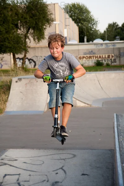 Boy rides scooter in a skate park — Stock Photo, Image