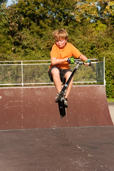 Boy rides scooter in a skate park — Stock Photo, Image