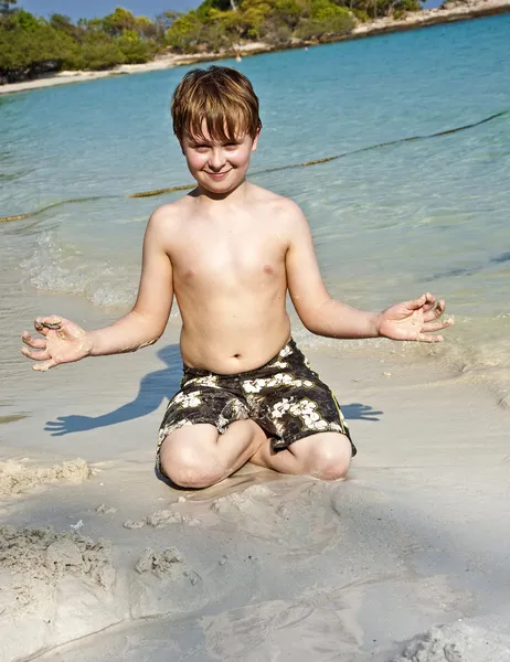 Fiú játszik a tengerparton homok és épület adatok — Stock Fotó