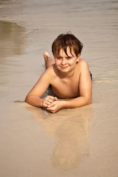 男孩要躺在沙滩上，享受水的暖意 — 图库照片