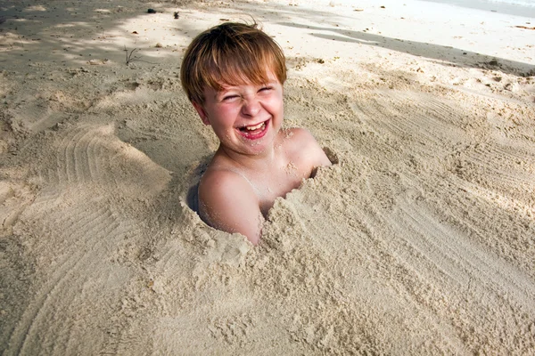 Boldog fiatal fiú hatálya a finom homok a strandon — Stock Fotó