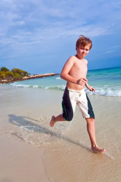수영복에 붉은 머리를 가진 어린 소년 해변을 따라 실행 — 스톡 사진