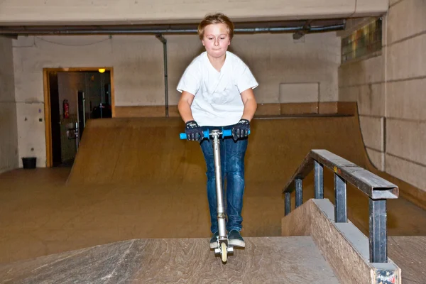 Rapaz a saltar com uma scooter sobre uma rampa — Fotografia de Stock
