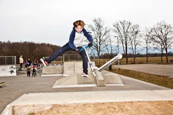 Pojken hoppar med en skoter över en ramp — Stockfoto