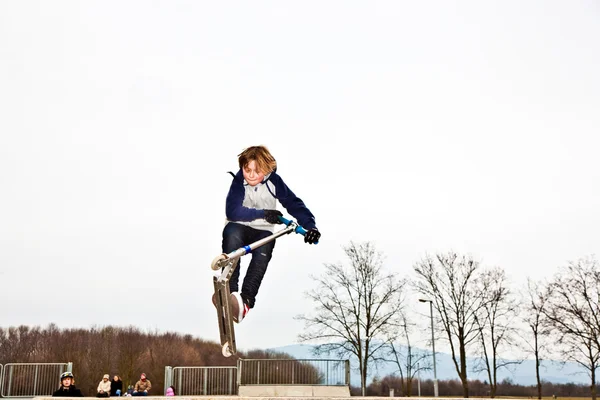 Garçon sautant avec un scooter sur une rampe — Photo