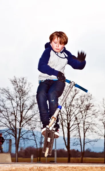Boy jumping with a scooter over a ramp — Stock Photo, Image