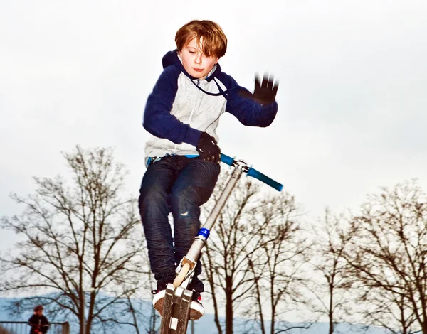 Chlapec skákání přes rampu s skútr — Stock fotografie